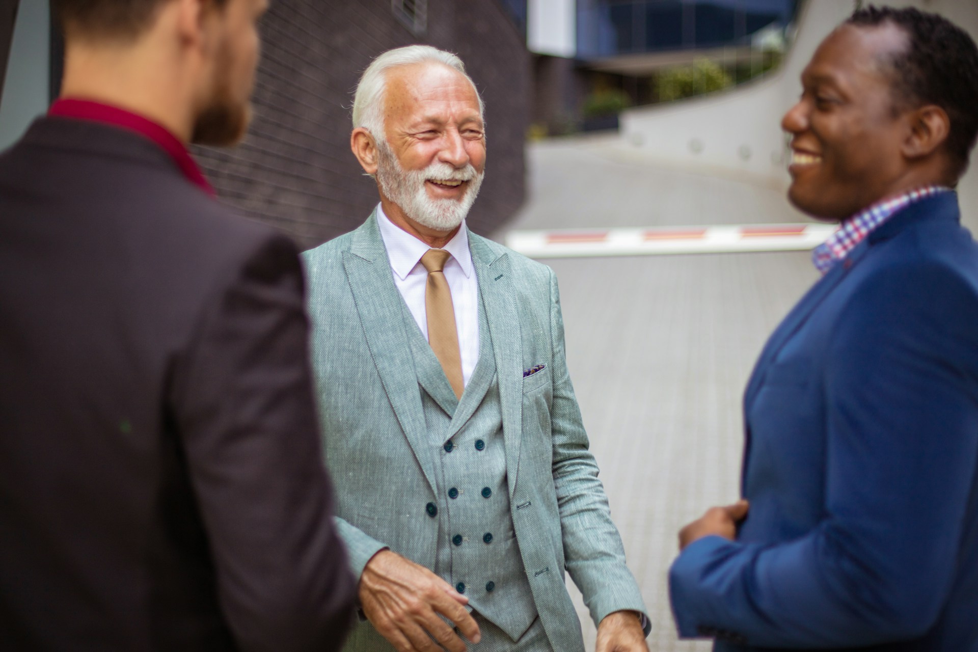 Three business partners in suits smiling while discussing strategy